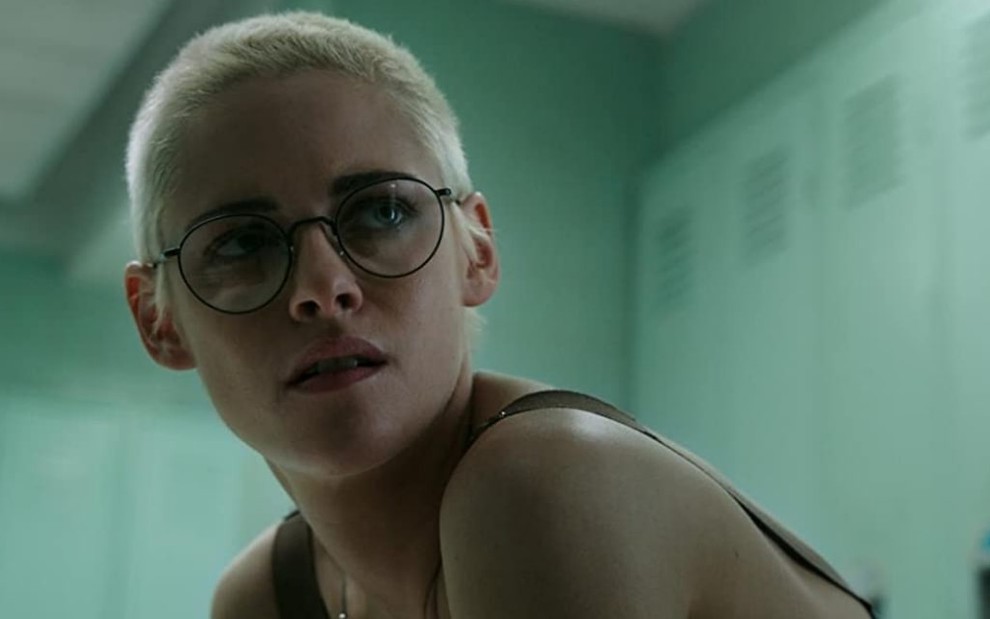 Com cabelos loiros e quase raspados, Kristen Stewart está com expressão séria em um vestiário no filme Ameaça Profunda (2020)