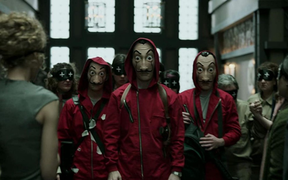 Os assaltantes armados, com roupas vermelhas e máscaras de Salvador Dalí em cena da quarta temporada de La Casa de Papel