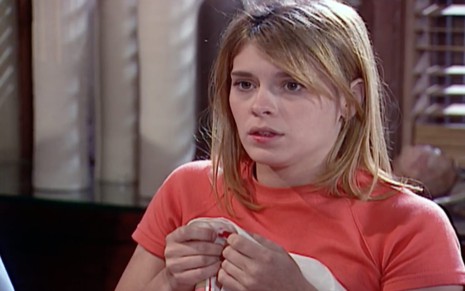 A atriz Carolina Dieckmann com camiseta laranja e expressão assustada em cena de Laços de Família