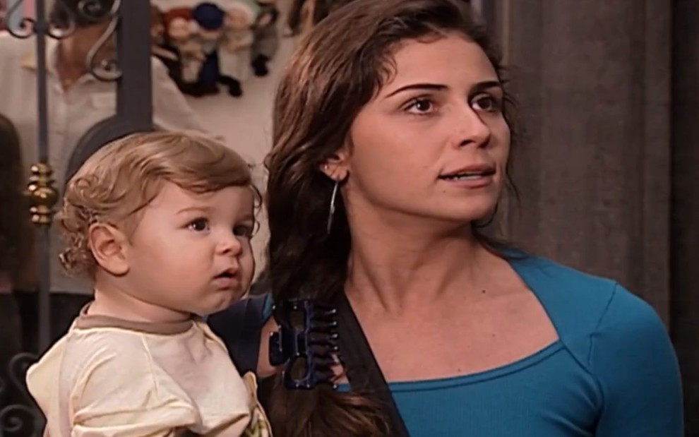 A atriz Giovanna Antonelli com expressão irritada e com o bebê que interpretava seu filho em cena de Laços de Família