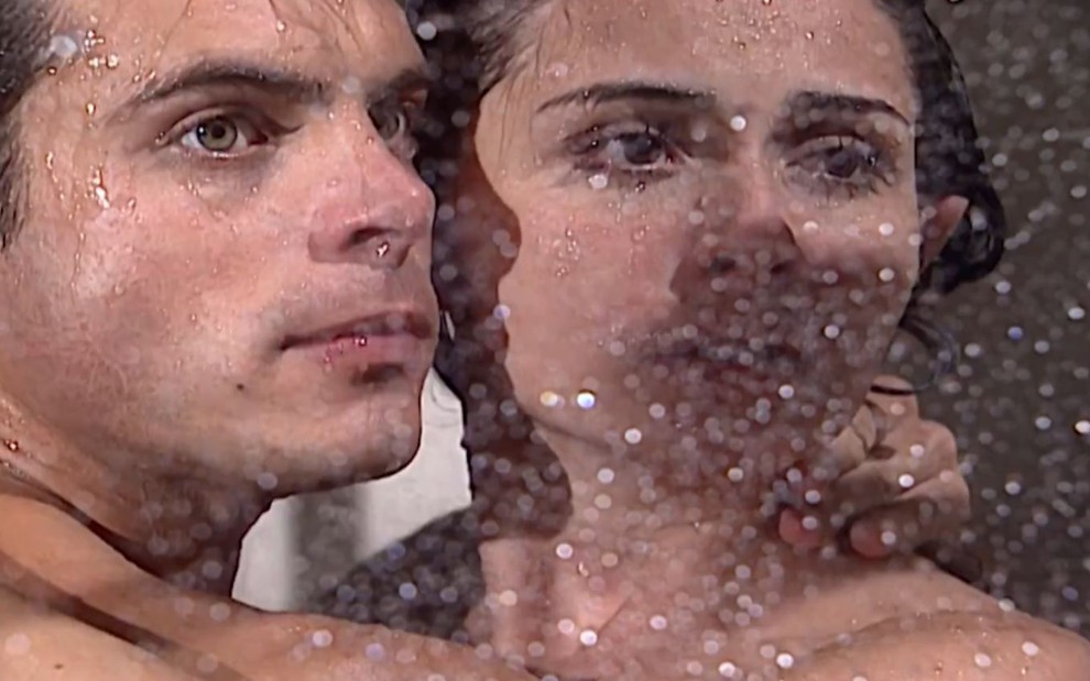 Os atores Luigi Baricelli e Giovanna Antonelli de rostos colados, olham com expressões sérias em cena de banho em Laços de Família