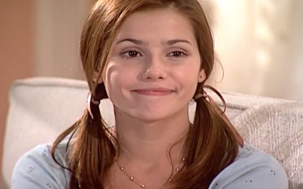 A atriz Deborah Secco com sorriso irônico em cena como Íris de Laços de Família