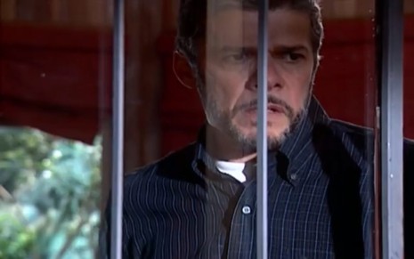 O ator José Mayer com expressão chateada em frente à janela em cena de Laços de Família