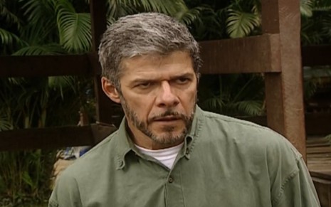 O ator José Mayer com expressão séria e camisa verde em cena de Laços de Família no haras