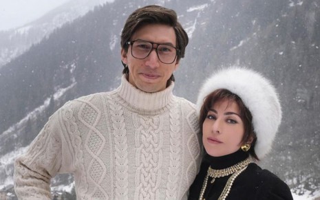 Adam Driver e Lady Gaga caracterizados como Maurizio Gucci e Patrizia Reggiani usando roupas de frio em ambiente de neve