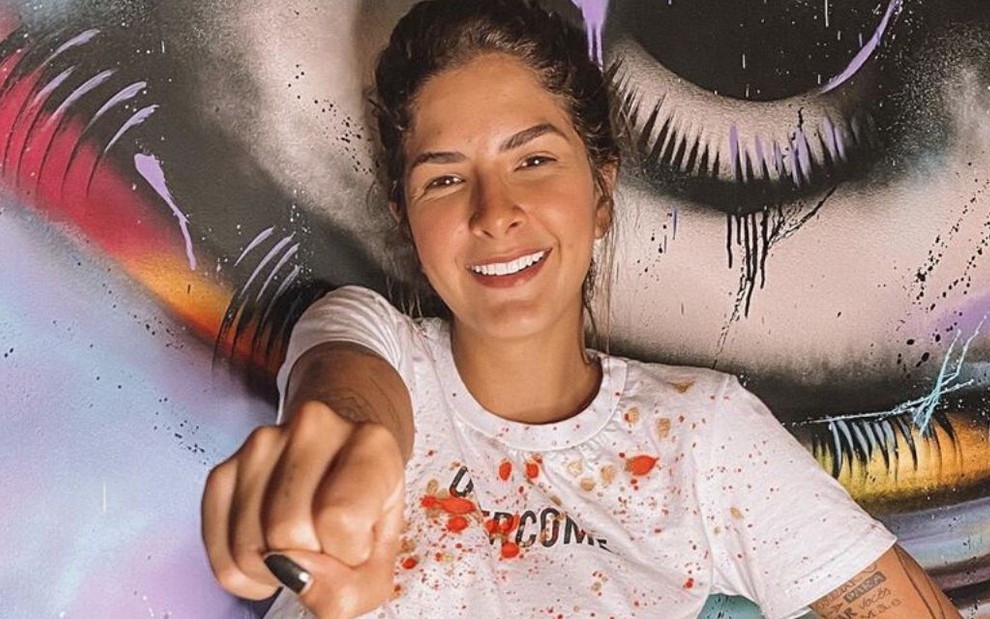Laryssa Bottino, amiga de Anitta, sorrindo com o braço estendido em foto publicada nas redes sociais