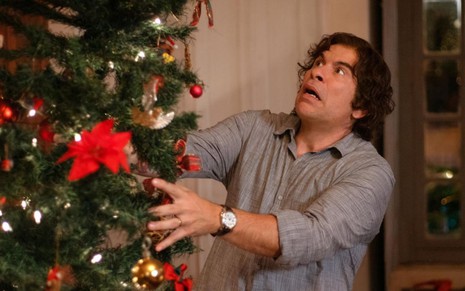 Imagem de Leandro Hassum tentando segurar uma árvore de Natal em cena do filme Tudo Bem no Natal que Vem