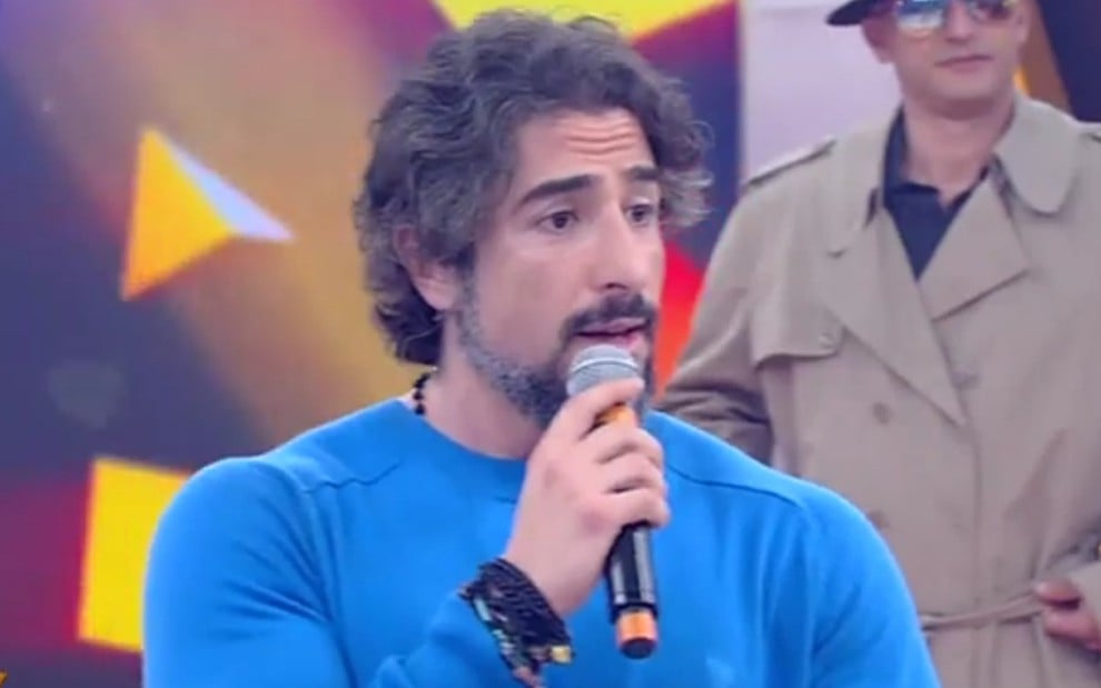 Marcos Mion fala ao microfone no palco do programa Legendários