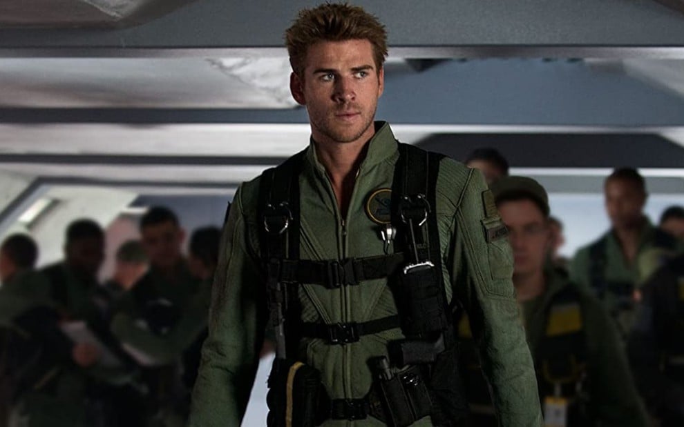 Liam Hemsworth usa um uniforme verde e está na frente de várias pessoas em cena do filme Independence Day - O Ressurgimento
