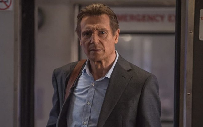 Liam Neeson de pé em um vagão de trem em cena do filme O Passageiro (2018)