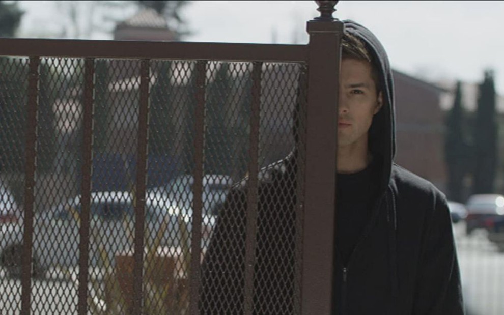 O ator Travis Burns olha com expressão doentia, por trás de um portão, em cena do filme O Vizinho Psicopata