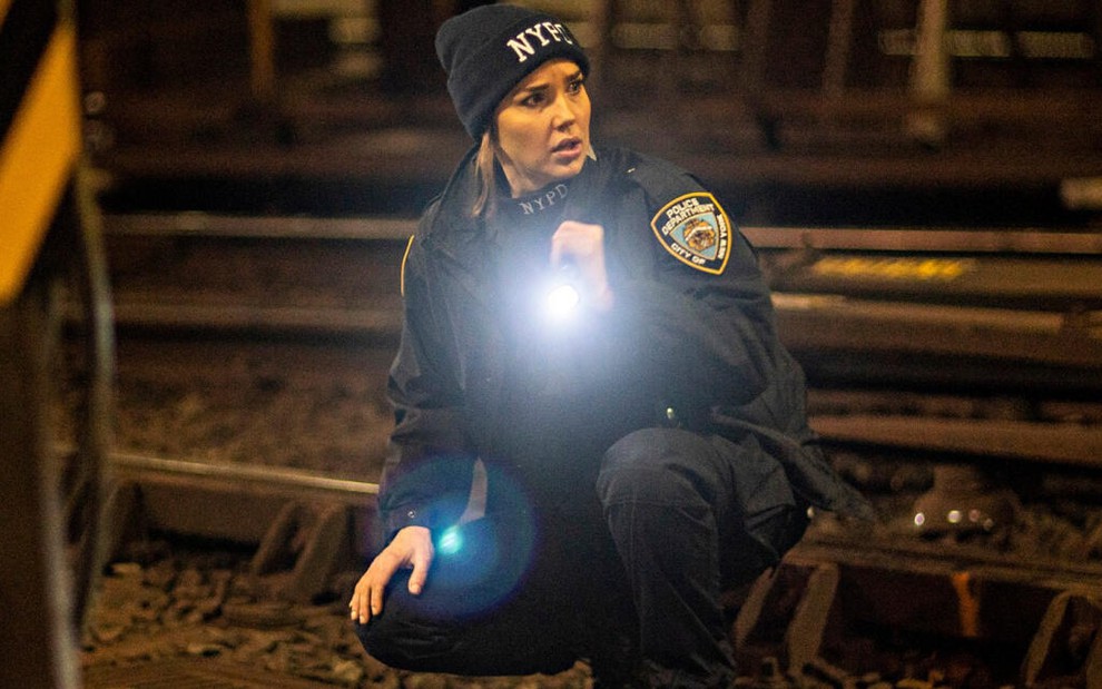 Com roupa de policial, a atriz Arielle Kebbel acende uma lanterna dentro de um túnel do metrô de Nova York, em Lincoln Rhyme