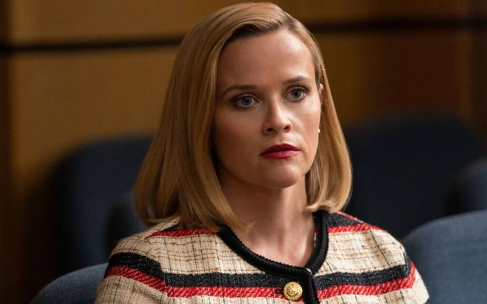 Sentada em um banco de um tribunal, a atriz loira Reese Witherspoon se espanta em cena de Little Fires Everywhere