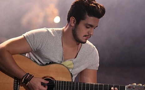 Sentado, o sertanejo Luan Santana toca violão e olha para baixo em imagem publicada no Instagram