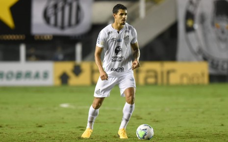 Lucas Veríssimo em jogo no campo do Santos, vestido com o uniforme branco do time