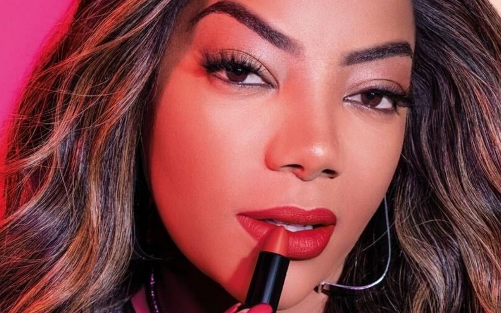 Ludmilla posa como garota-propaganda da Avon com um batom nas mãos 