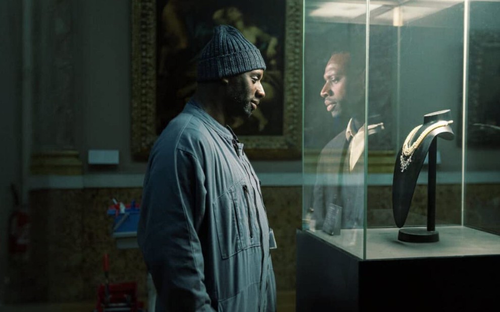 Omar Sy olha um colar no Museu do Louvré em cena da série Lupin