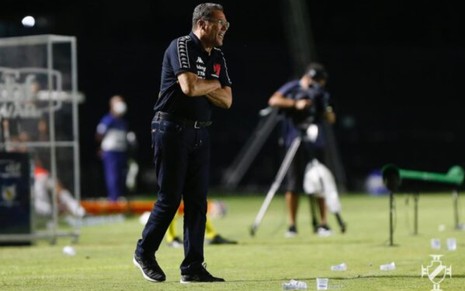 O técnico do Vasco, Vanderlei Luxemburgo na lateral de braços cruzados, ele veste calça jeans escuro, camisa preta com escudo do time e tênis preto
