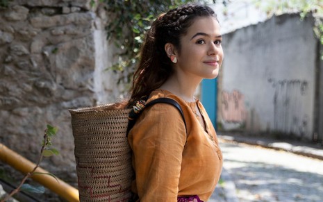 Maisa Silva sorri e usa uma roupa de hippie em cena do filme Pai em Dobro (2020)