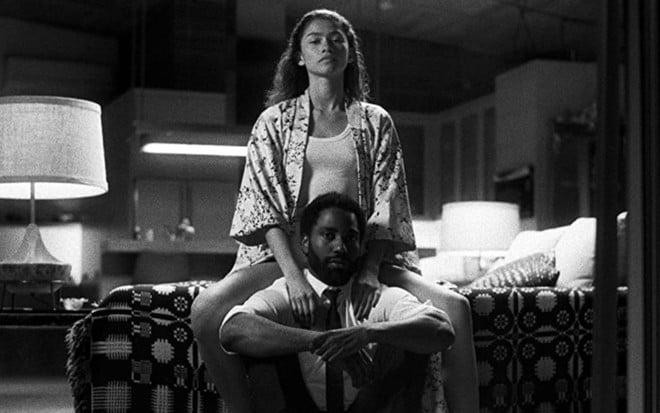 Zendaya abraça John David Washington sentada na cama em foto do filme Malcolm & Marie