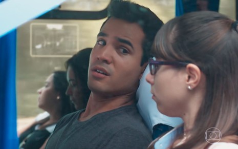 Os atores Bruno Gadiol e Daphne Bozaski lado a lado em ônibus de viagem em cena de Malhação