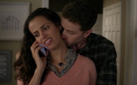 Enquanto fala ao celular, Athena Karkanis recebe um abraça e ganha um beijo no pescoço dado de Josh Dallas, em Manifest