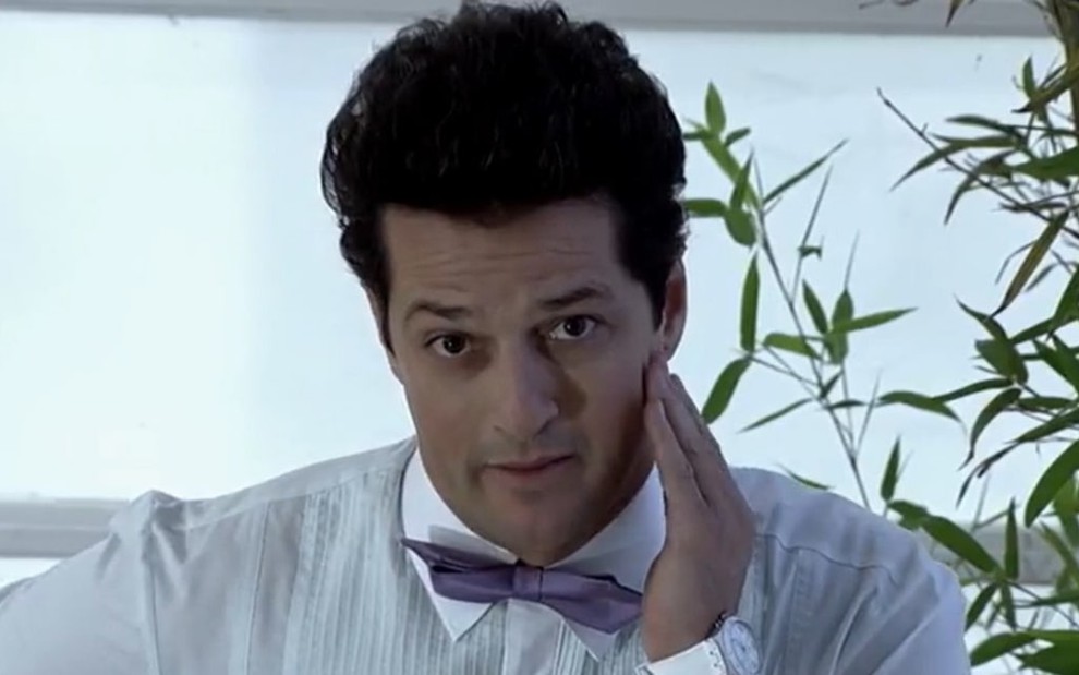 O ator Marcelo Serrado com expressão de dúvida em cena como Crô de Fina Estampa
