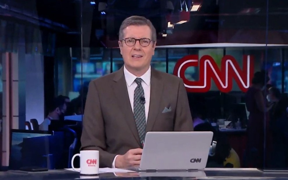 Márcio Gomes no CNN Prime Time, de terno, óculos, sentado na bancada