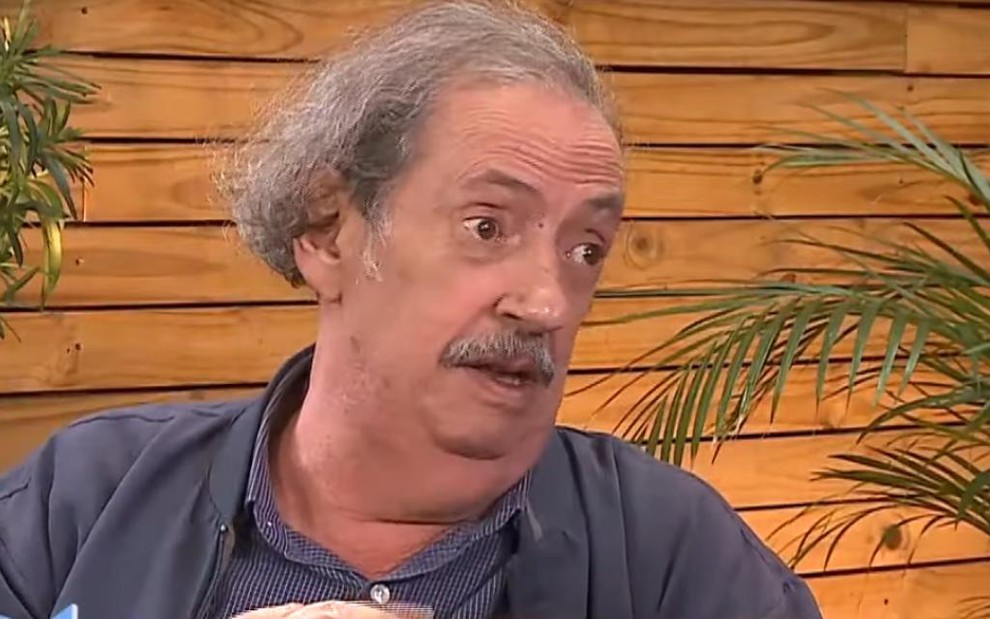 O ator Marcos Oliveira em entrevista à RedeTV! em 2019, com cenário de madeira e plantas 