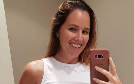 A cantora Mariana Belém posou sorridente para uma selfie, de cabelo solto e blusa branca
