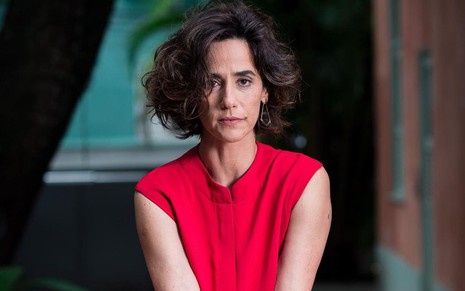 A atriz Mariana Lima, com uma roupa vermelha, posando para foto com expressão séria