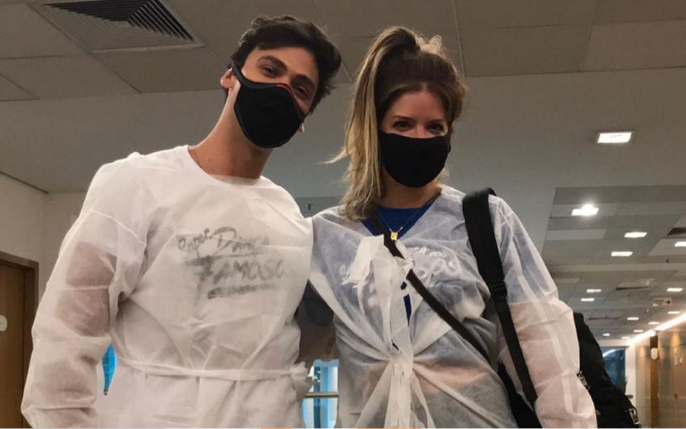 Na foto, Élcio Bonazzi e Mariana Santos posam usando máscaras pretas e avental descartável