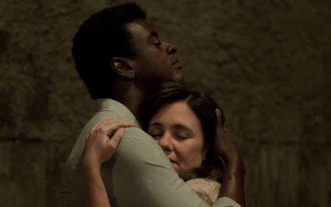 Seu Jorge e Adriana Esteves abraçados em cena de filme Marighella