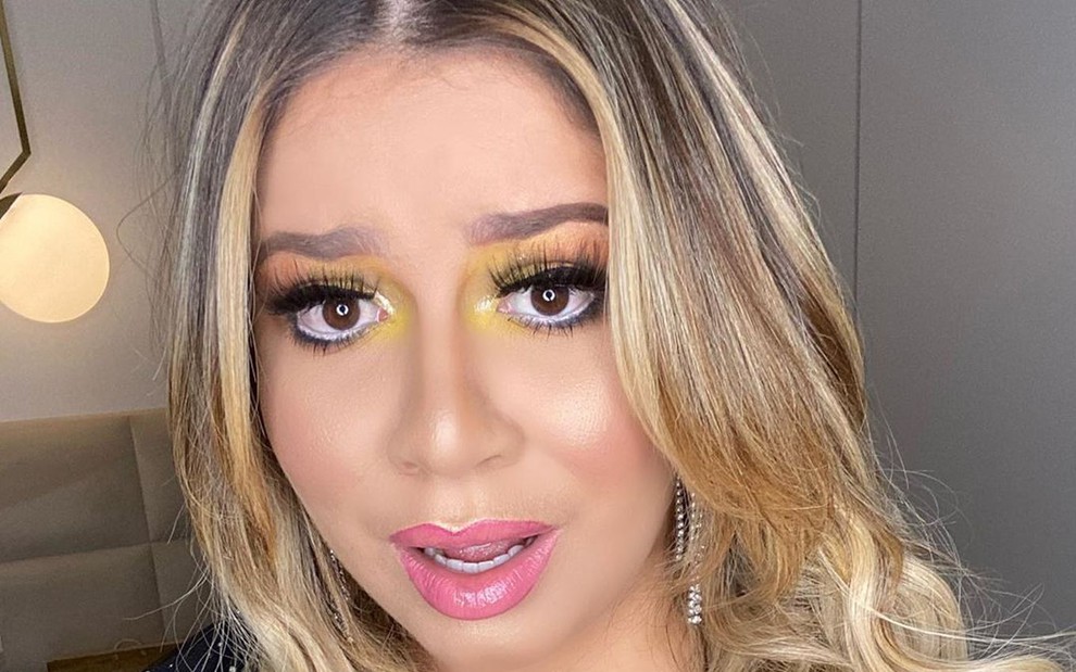 Marília Mendonça com expressão de indignação em selfie, com maquiagem colorida