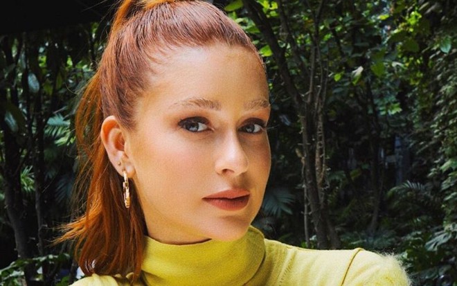 Imagem de Marina Ruy Barbosa com o cabelo preso e uma blusa de gola alta amarela