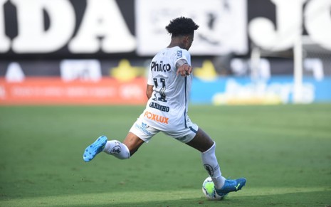 Marinho, jogador do Santos, em lance com a bola no pé, vestido com o uniforme do time na cor branca
