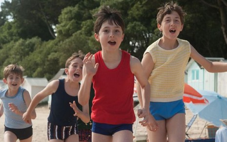 Mathéo Boisselier e seus amigos correm na praia em cena de As Férias do Pequeno Nicolau