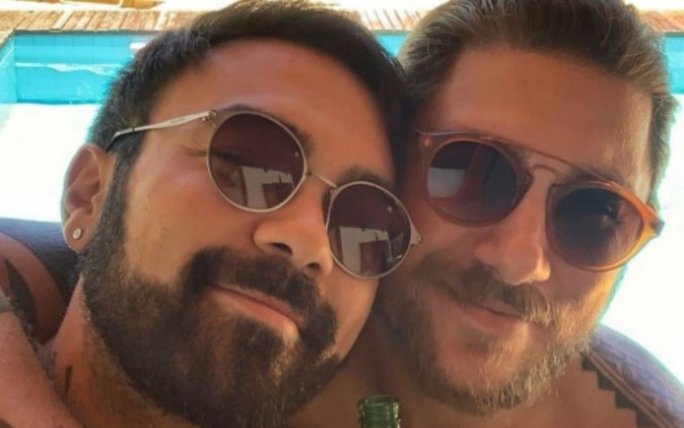 Mauro Sousa e Rafael Piccin usam óculos escuros enquanto sorriem para foto em estilo selfie