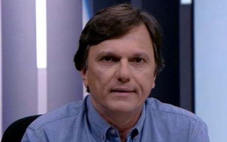 Mauro Cezar, comentarista da ESPN Brasil, aparece de camisa azul e franja penteada para o lado esquerdo da imagem