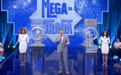 Luigi Baricelli no estúdio com duas assistentes de palco no sorteio da Mega da Virada em 2019