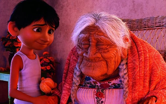 De pé, Miguel observa a Mamá Inês (que está sentada) em cena de Viva: A Vida é Uma Festa (2018)
