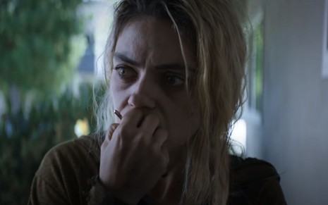Mila Kunis com olhar assustado e mãos à frente da boca em cena do filme Four Good Days