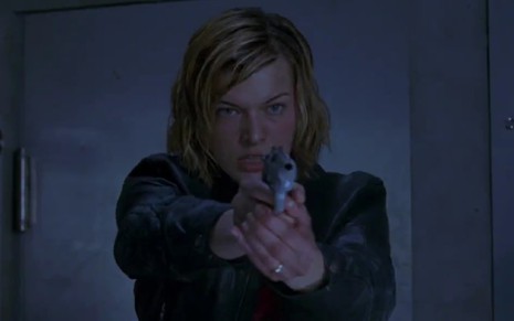 Milla Jovovich como Alice segurando uma arma em Resident Evil - O Hóspede Maldito