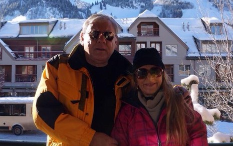 Milton Neves e Lenice posam com óculos escuros e casacos de frio em uma estação de esqui