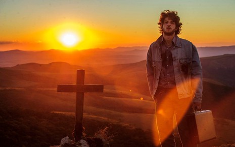 Chay Suede interpreta José Alfredo e posa no alto do Monte Roraima, junto com a cruz onde Sebastião foi enterrado. Ao fundo da foto, o Sol se põe.