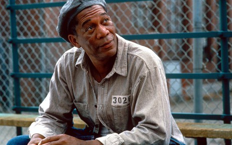 Com roupa de preso e numa área de recreação da cadeia, Morgan Freeman faz cara de conformado em cena de Um Sonho de Liberdade