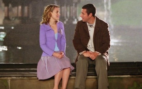 Winona Ryder e Adam Sandler conversam sentados ao lado de uma fonte em A Herança de Mr. Deeds (2002)