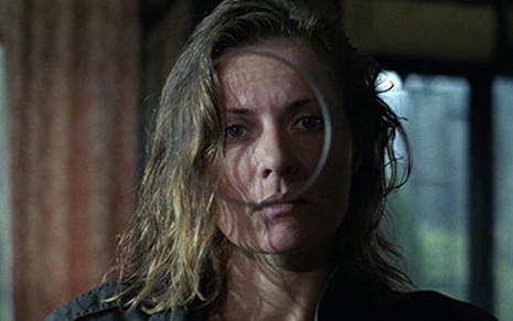 A atriz Grazyna Szapoloswka caracterizada como Magda em cena de Não Amarás, ela olha através de um círculo em uma barreira de virdro