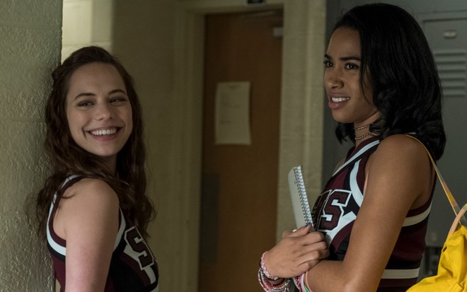Marlo Kelly abre um sorrisão enquanto Herizen Guardiola, de mochila branca e com caderno na mão, faz care de enjoada