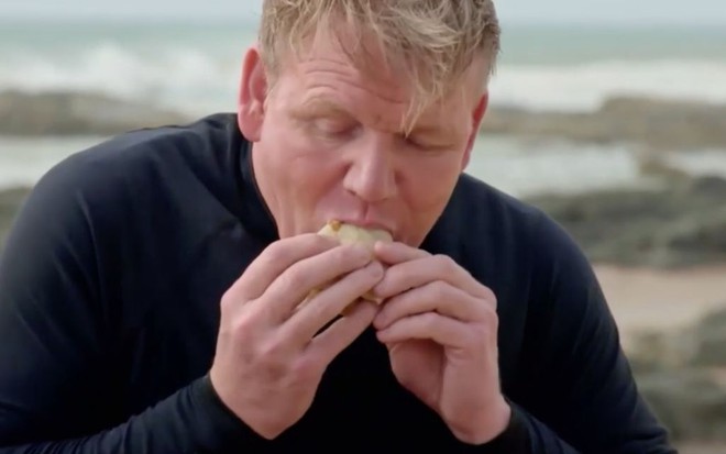 O chef de cozinha Gordon Ramsay comendo um sanduíche no programa Sabores Extremos, do canal NatGeo